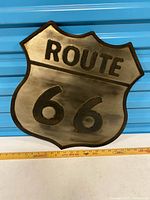Front view of metal Route 66 shield sign beside ruler