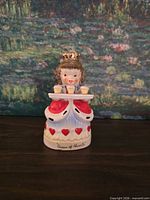 Front view of Queen of Hearts figurine showing multicolor paint, tray with cups, red hearts on skirt, base inscription visible