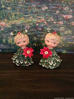 Front view of both girl figurine shakers showing colors and letters