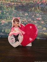 Front of planter showing girl figurine on white heart and red heart