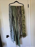 All four scarves hanging on hanger showing colors, patterns, fringed ends