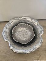 Two nested pewter bowls showing size difference and relief designs