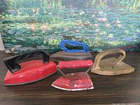 Front view of four toy irons displaying handles and paint colors