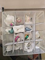 Top tier of storage box showing ball and pinecone ornaments in cardboard dividers