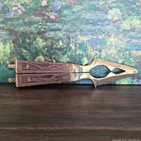 Closed nutcracker on table showing carved wood handles and brass jaws