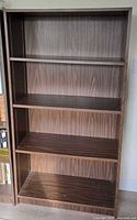 Full front view of walnut laminate bookcase showing four shelves and overall condition