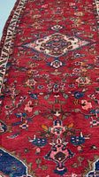 Close-up of rug field highlighting red wool pile, central motifs and colors