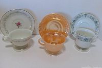Front view of three cup and saucer sets on stands