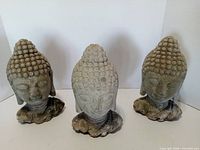 Front view of three Buddha head statues showing overall condition