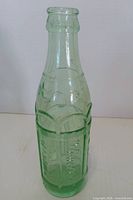 Full view of light green embossed soda bottle