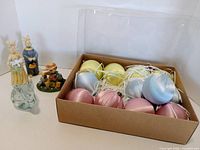 Group shot showing glass bunny, three resin rabbit figurines, boxed pastel eggs