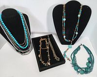 Group shot of six blue-tone jewellery pieces on displays and tray