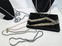 All necklaces displayed on two busts and tray, showing arrangement