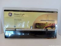 Front of sealed GE picture light kit packaging showing branding and 16-inch fixture