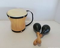 Wooden hand drum and pair of maracas upright on surface