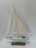 Front view of wooden sailboat model showing sails, hull, stand