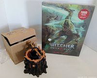 Front view of sealed Witcher puzzle, resin cauldron on stand, and original cardboard box