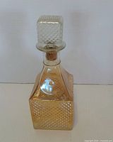Full frontal view of square amber carnival glass decanter with stopper
