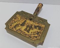 Top view showing carved panel, brass body, decorated handle