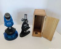 Both microscopes and wooden case side by side