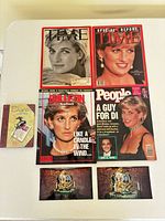 Front covers of four magazines, booklet, two photo prints displayed on table