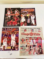 Overview of four Clemson men’s basketball publications: two paperback media guides, one spiral-bound media guide, and one Orange & White newspaper