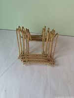 Gold-tone plated metal plate rack showing rope-twist construction and arched dividers