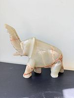 Front left view of polished onyx elephant showing veining and raised trunk