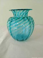 Front view of aqua-teal handblown glass vase showing swirled ribbed pattern and flared rim