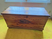 Closed cedar chest front view showing finish, oval medallion, feet