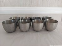Eight pewter Jefferson cups aligned rim to rim