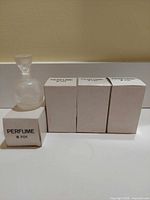 Perfume bottle with stopper beside four original boxes