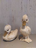 Standing and sitting ceramic duckling figurines side by side