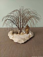 Front angled view of entire sculpture showing wire tree, brass figure, stone base