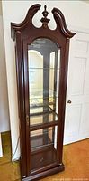 Full view of the curio cabinet showing arched top, glass door, overall finish