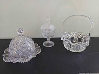 Group shot showing all three pressed glass pieces: butter dish with dome, lidded compote, handled basket