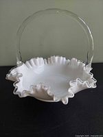 Front view of milk glass basket showing ruffled rim and clear handle
