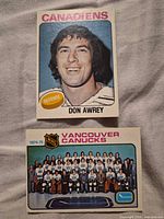Fronts of both hockey cards showing Don Awrey portrait and Vancouver Canucks team photo