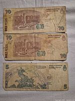 Reverse sides of two 10-peso and one 5-peso Argentine banknotes showing monuments and denomination