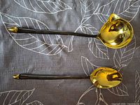 Top view of ladle and spoon showing gold-tone bowls and black handles