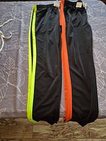 Full view of both legs showing green and orange side stripes and black fabric