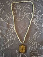 Full view of faux pearl necklace with pendant