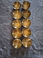 Top view of all ten small brass bowls showing uniform size and brass finish