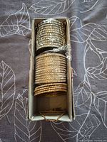 Top view of box showing stacks of rhinestone bangles in gold and silver tones