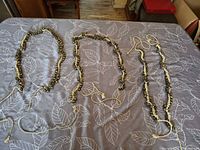 Overview of three of the braided bell necklaces laid out on table