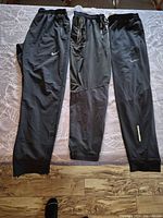 Front view of three black Nike joggers laid flat