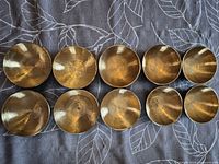 Top view of all ten brass singing bowls aligned in two rows