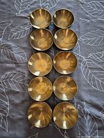 Top-down view of ten brass singing bowls arranged in two columns