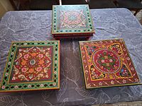 All three square hand-painted wooden stands on tabletop