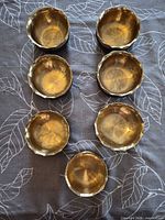 Top view of seven brass bowls showing polished interiors